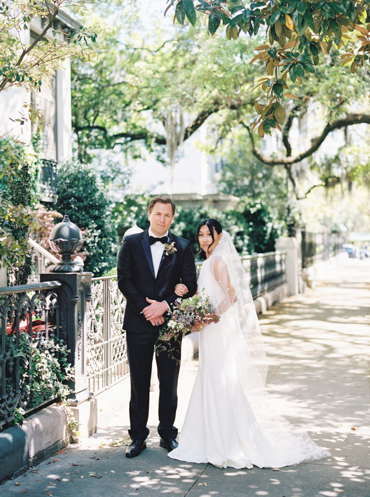 Bride and groom pose for a traditional portrait in the sun-soaked streets of Savannah, Georgia.