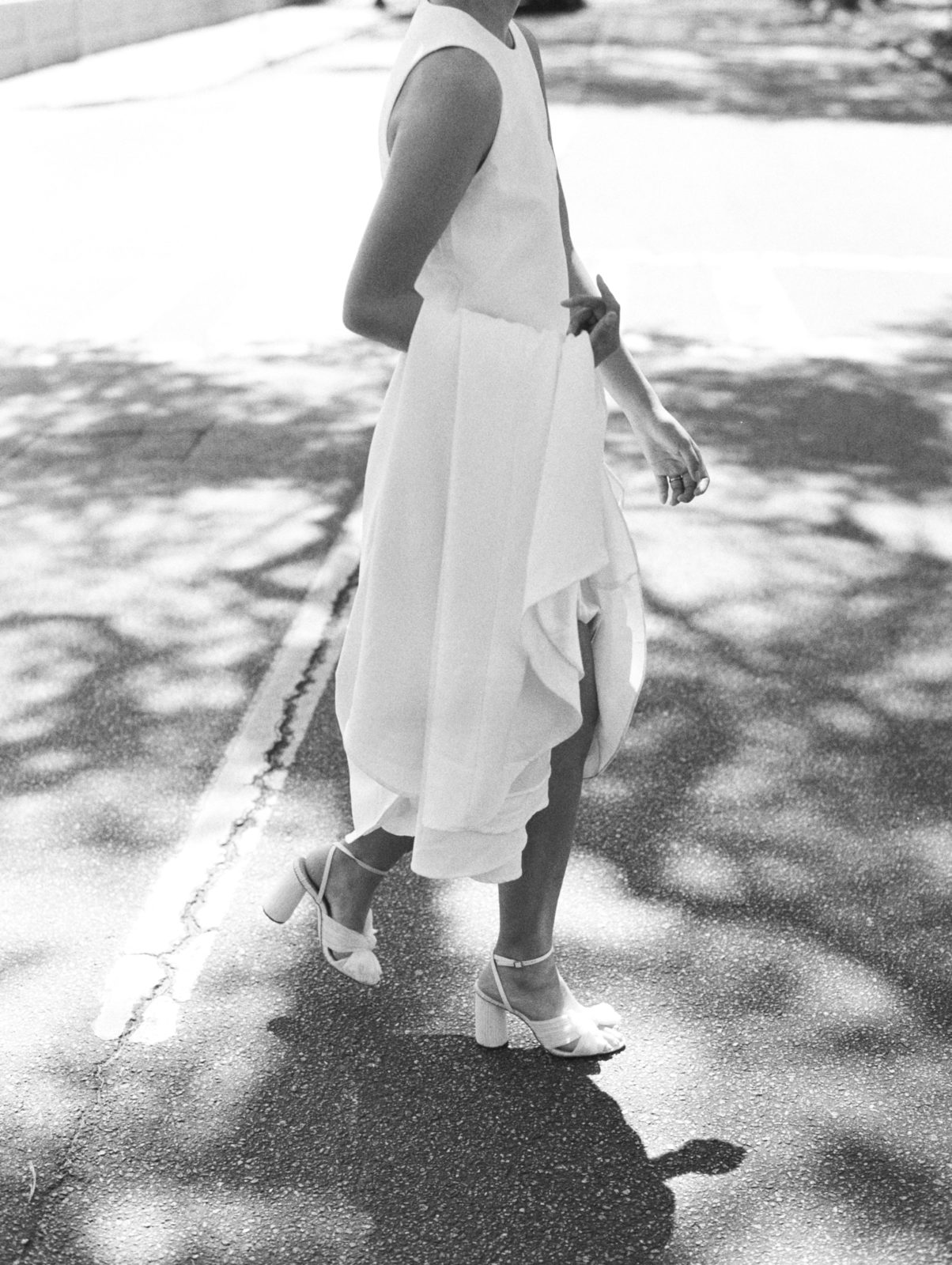 Bride holds modern dress while crossing the street during her old world-inspired elopement.