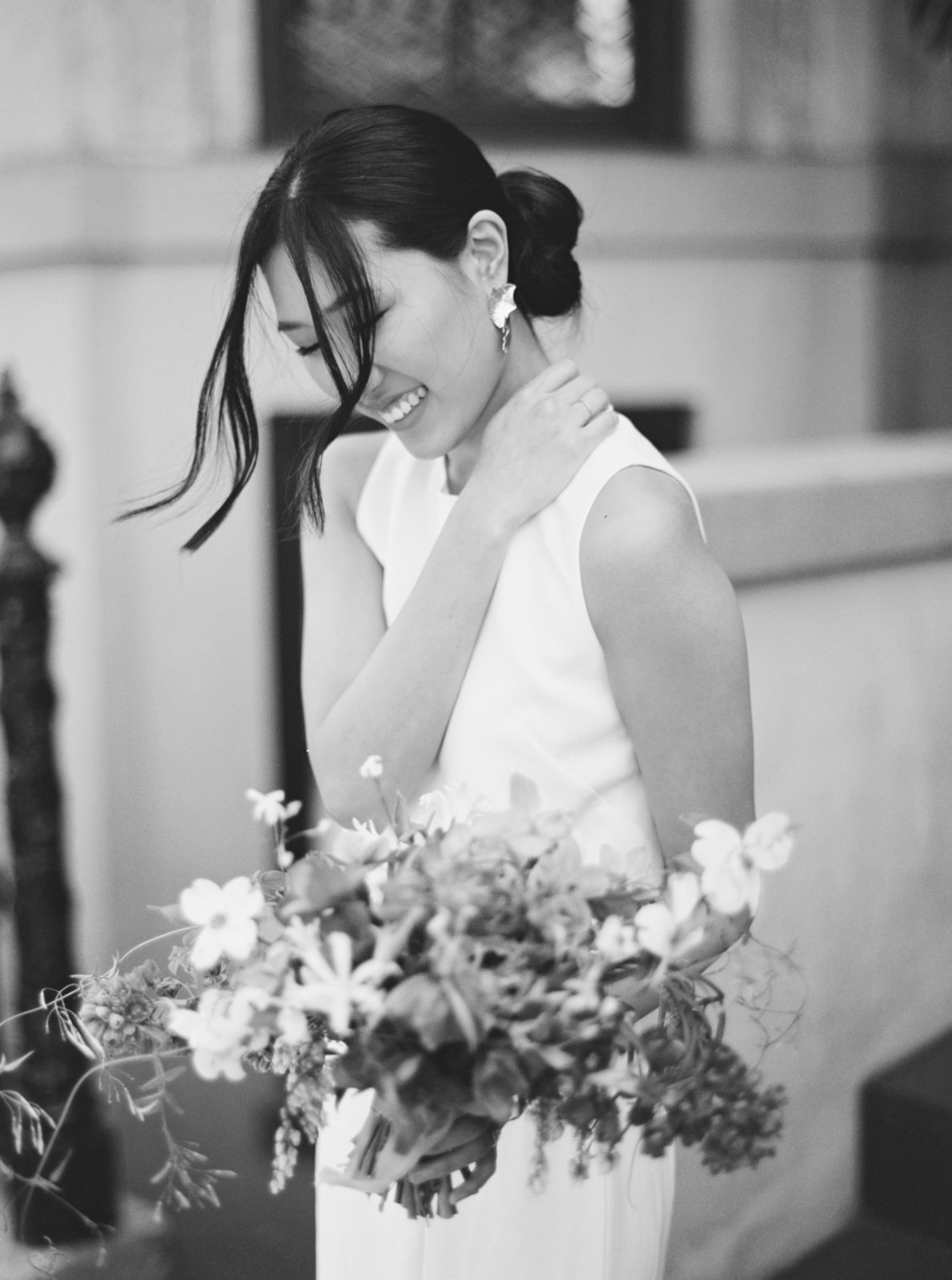Bride laughs while holding bouquet on black and white film in the streets of Savannah. Old world-inspired elopement. 