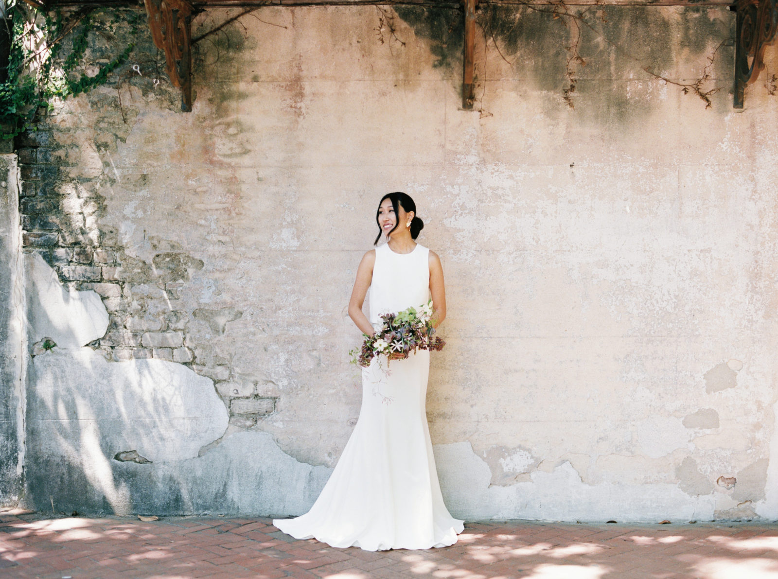 Bride smiles while holding organic bouquet for a portrait during her old world-inspired elopement in Savannah, Georgia.