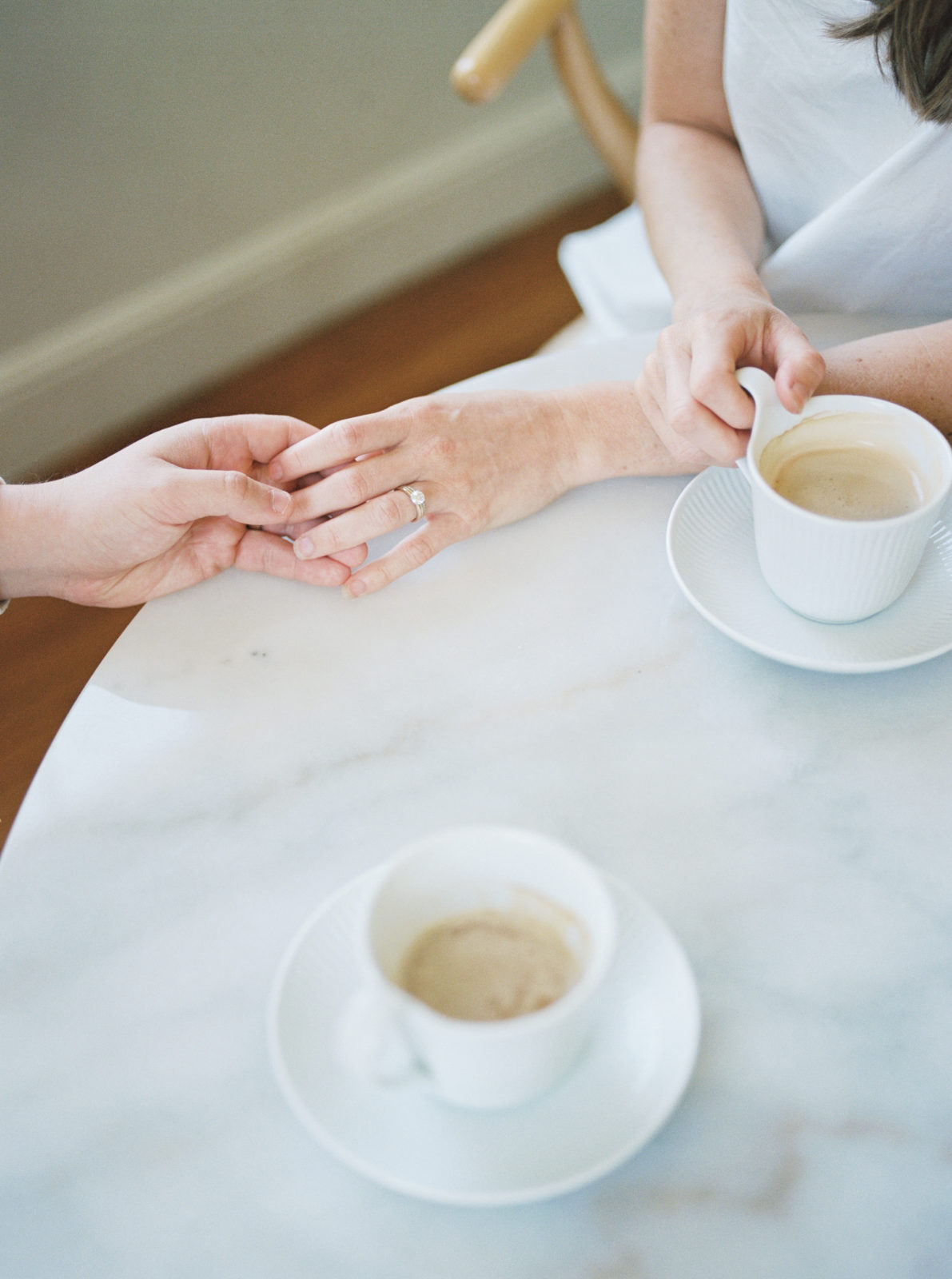 Nashville lifestyle in-home session. Husband grabs wife's hand while drinking coffee.