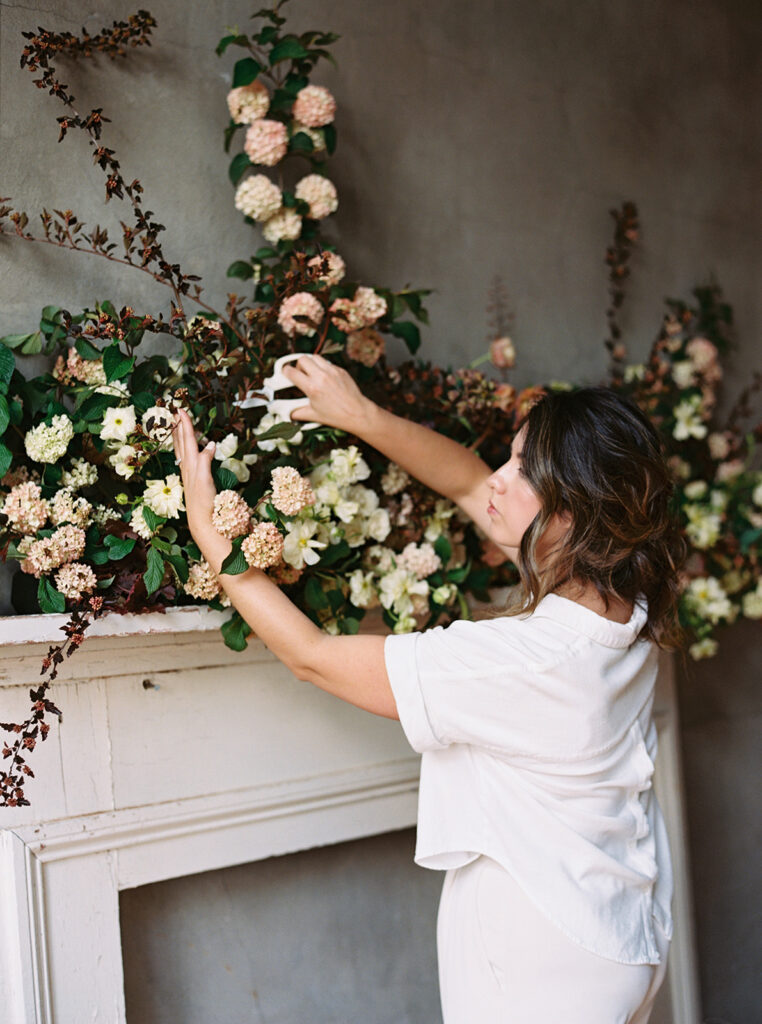 A floral designer trimming a mantle installation
