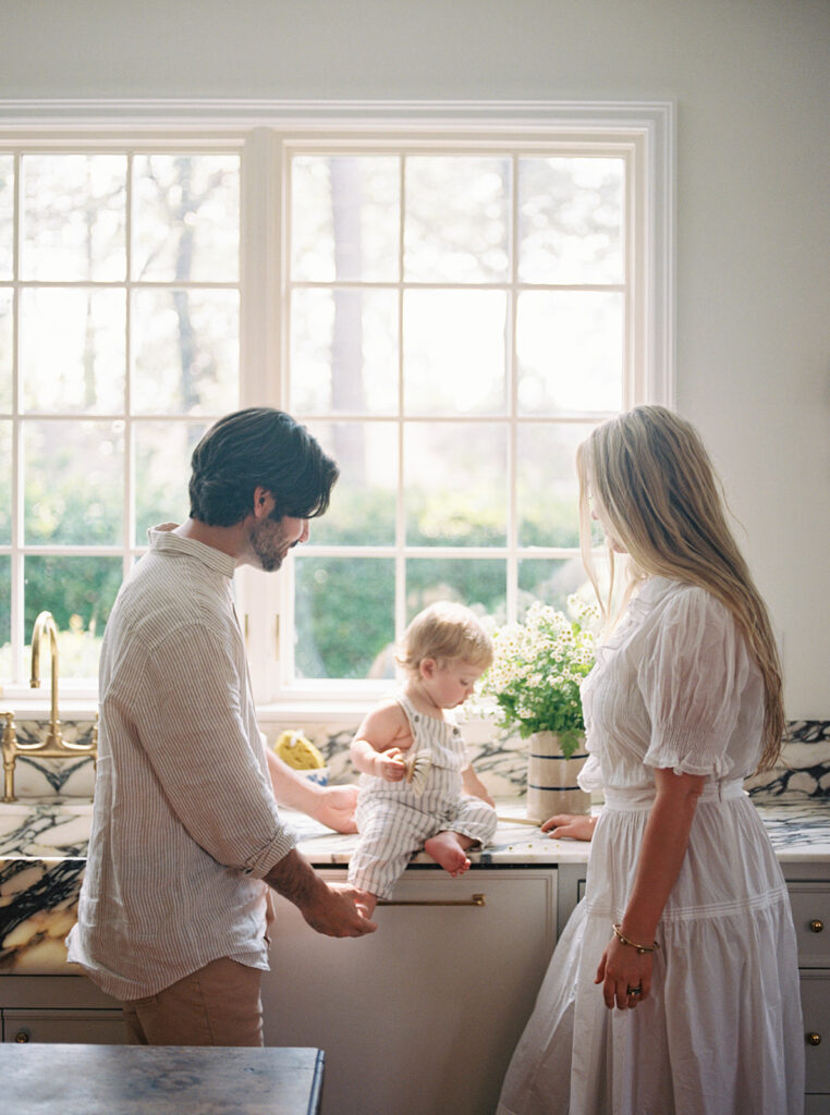 A lifestyle portrait in Carley Summers home of her and her husband with their son in the kitchen