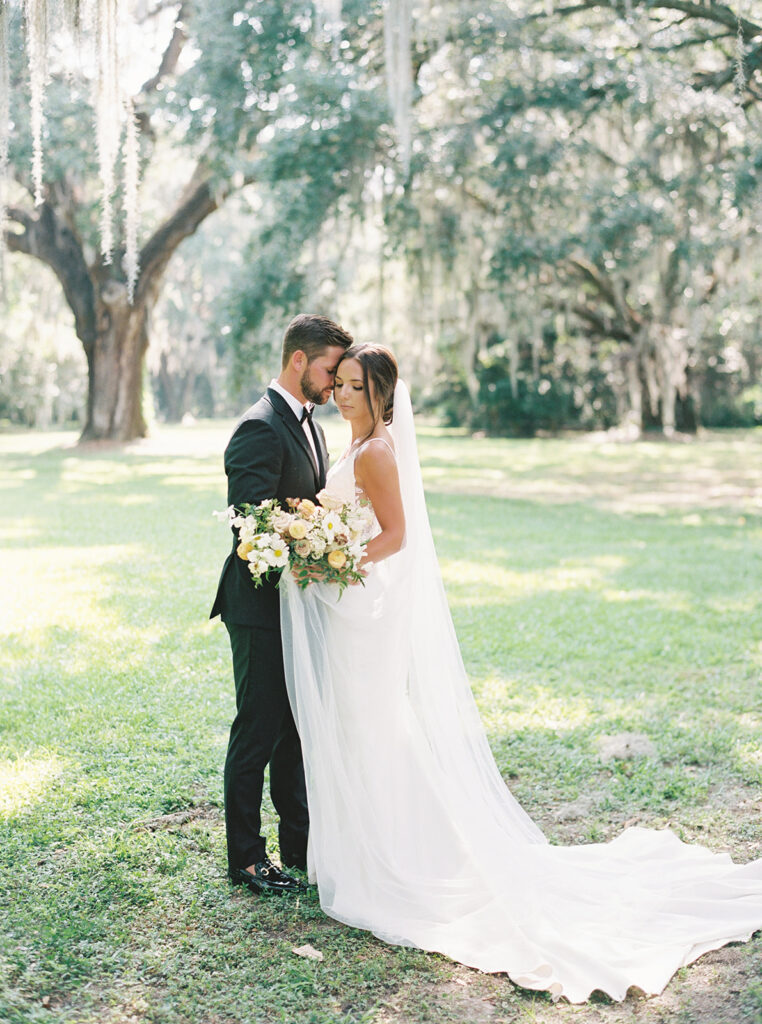 Groom holds bride close at Legare Waring House during their summer wedding in Charleston
