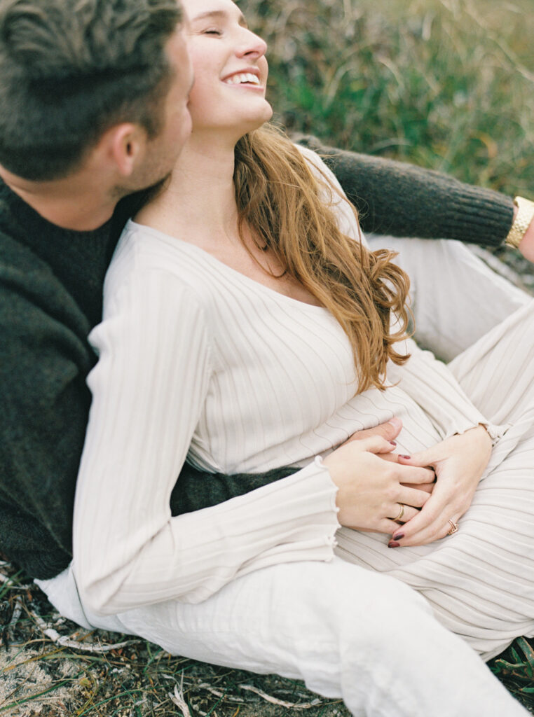 Couple cuddling and laughing during their early maternity session in Big Sur 