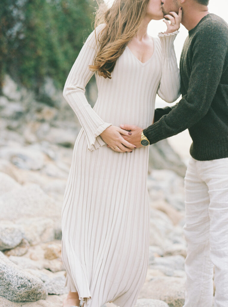 Couple kisses during their early maternity session in Big Sur at sunset