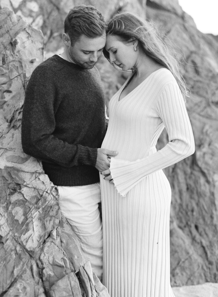 Couple holding mom's belly during early maternity session in Big Sur