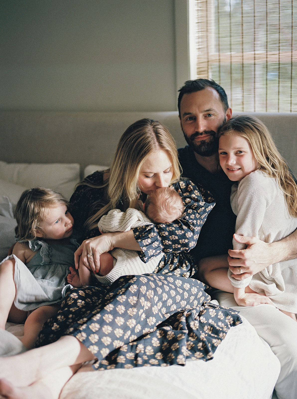 Candid photo of family sitting on bed with newborn baby for in-home family portrait session