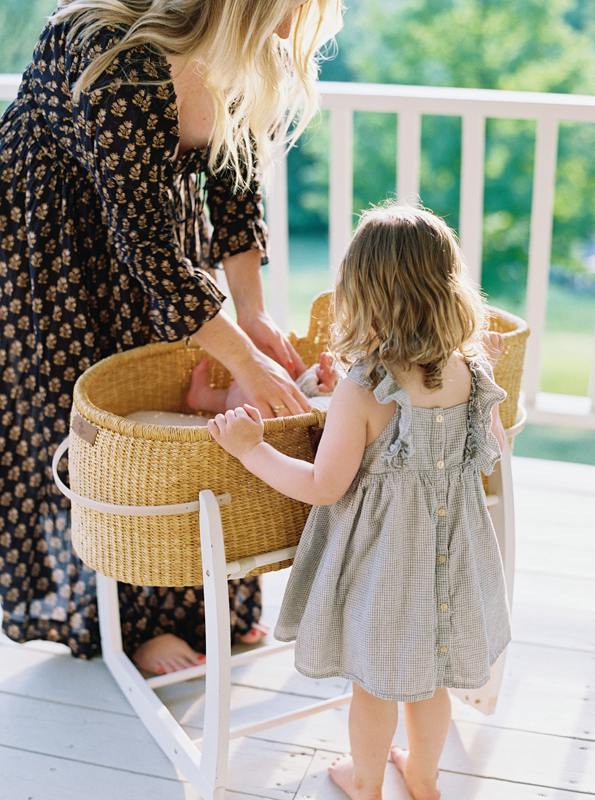 Mother places baby in moses basket during in-home family session in Nashville, Tennessee