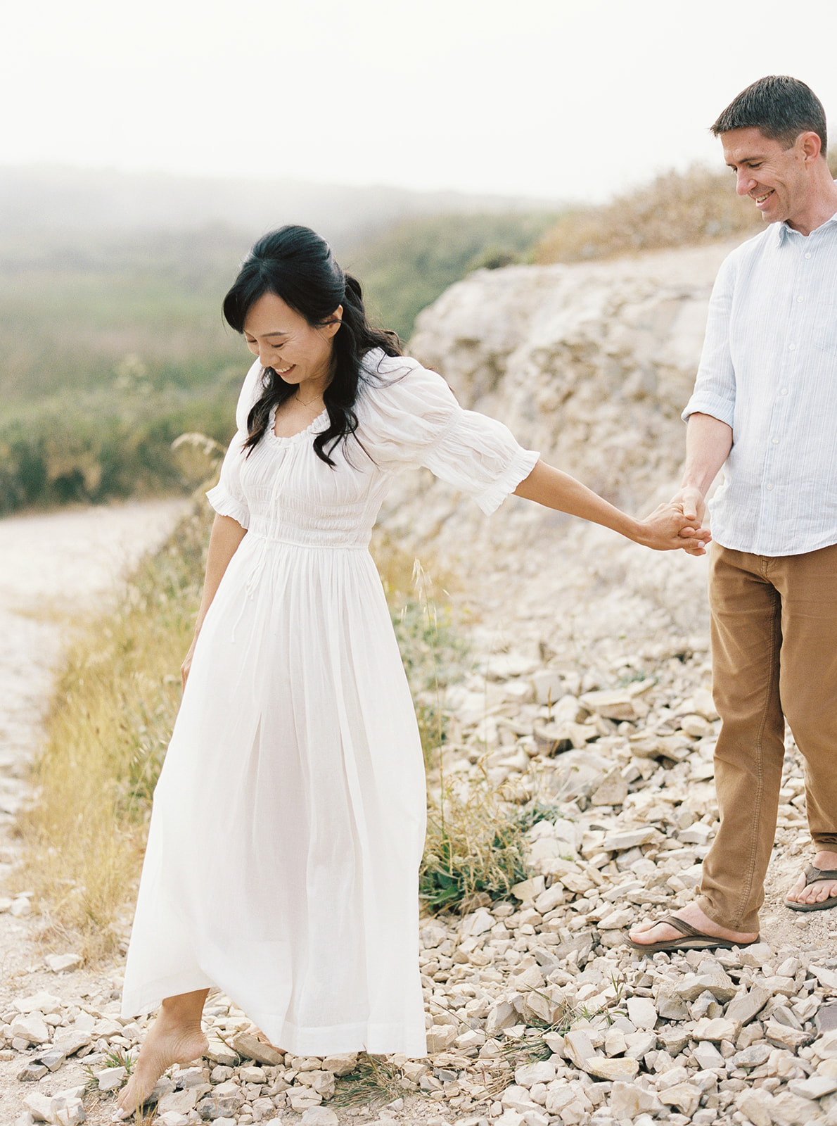 Husband and wife hold hands on the rocky shore of Santa Cruz during their Northern California family session